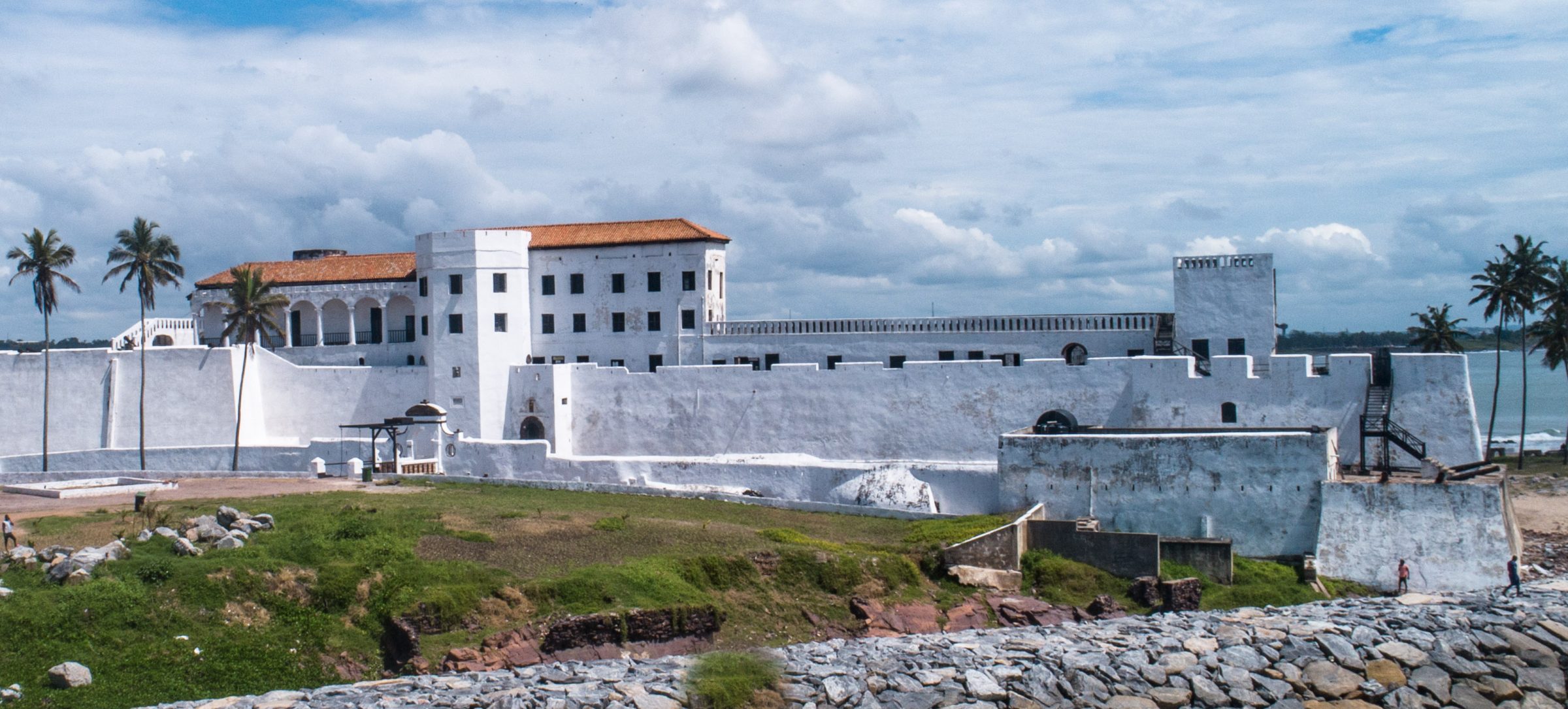 Elmina Castle seen from the air, its white walls set between the town and the Atlantic